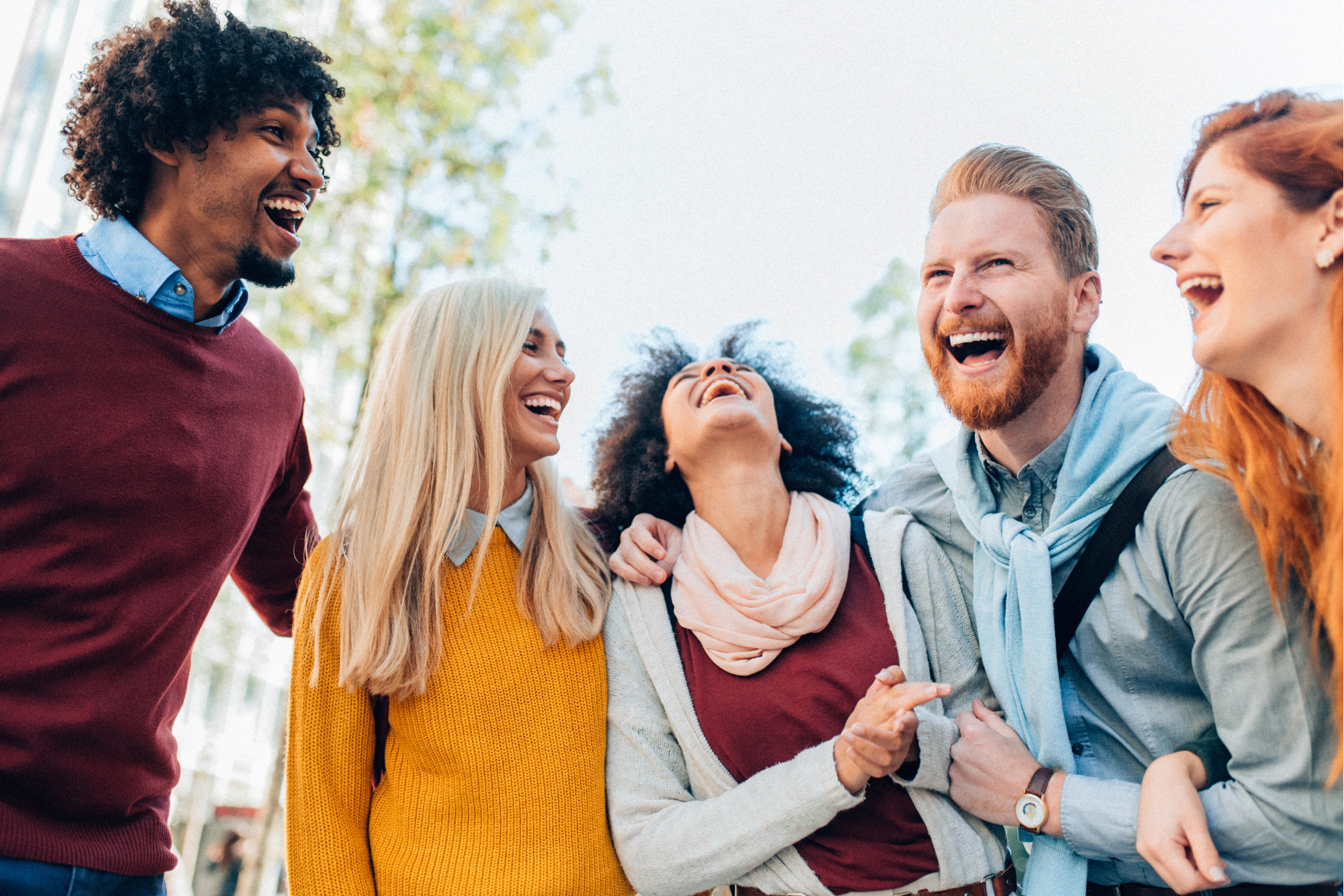 Num ambiente alegre, um grupo de pessoas sorri e ri, transmitindo calor humano e camaradagem.